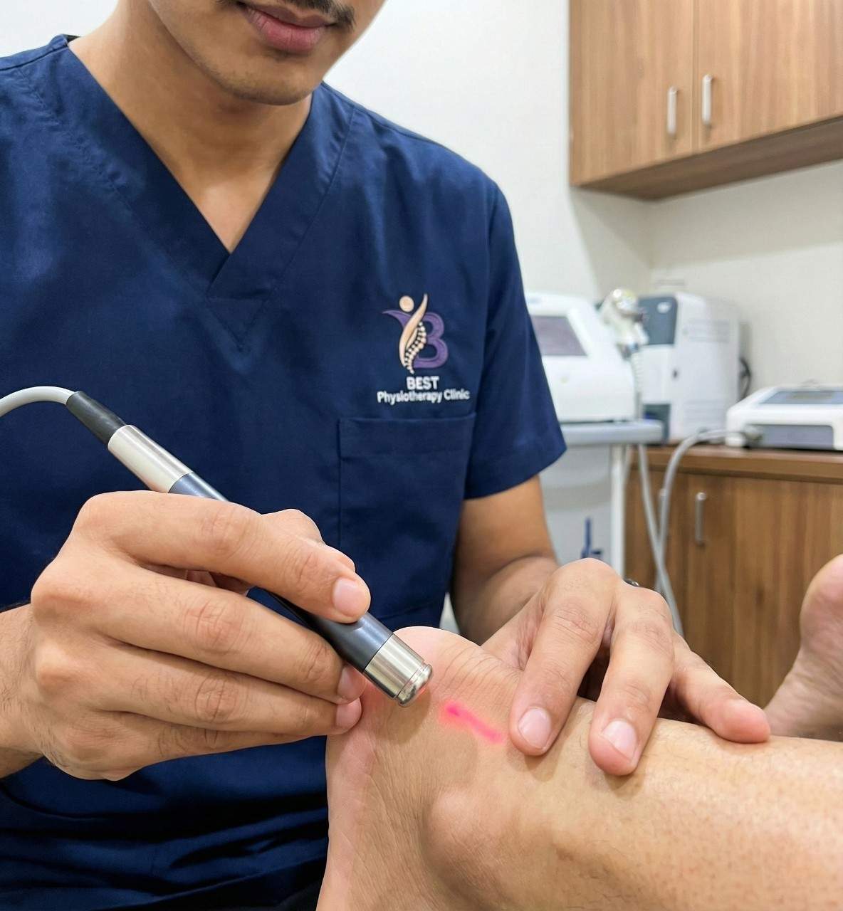 Close-up of a physiotherapist using a therapeutic laser device on a patient’s ankle area in Clinic Bopal Ahmedabad