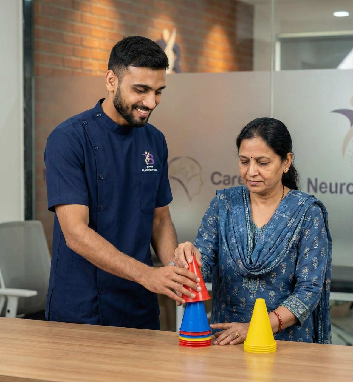 Physiotherapist assists an older woman with a fine motor skills exercise using colorful cones.